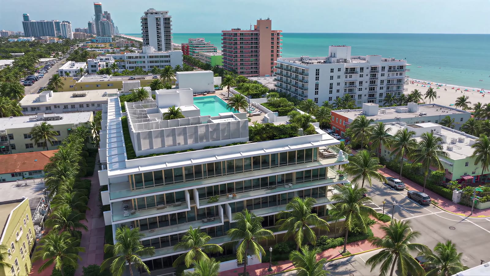 Aerial view of the 300 Collins residence on Collins Avenue in South Beach, Miami Beach, with its rooftop pool, palm trees and the ocean in the distance.