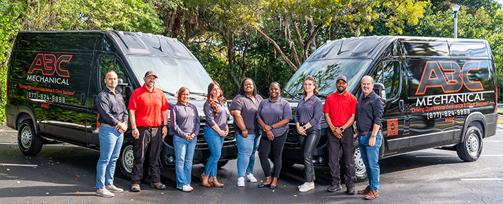 The ABC Mechanical team standing together in front of two branded service vans at the Fort Lauderdale headquarters